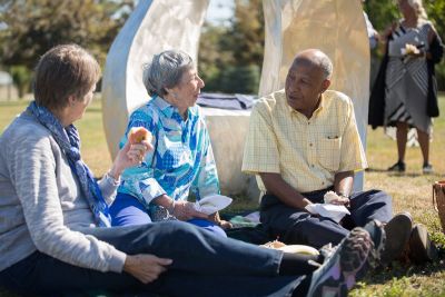 3 seniors sitting outside having a picnic together