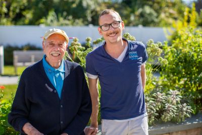 Smiling senior man with care provider outside on a walk at Peconic Landing