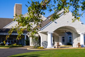 Front entrance building w/big white pillars & a covered drive at Peconic Landing