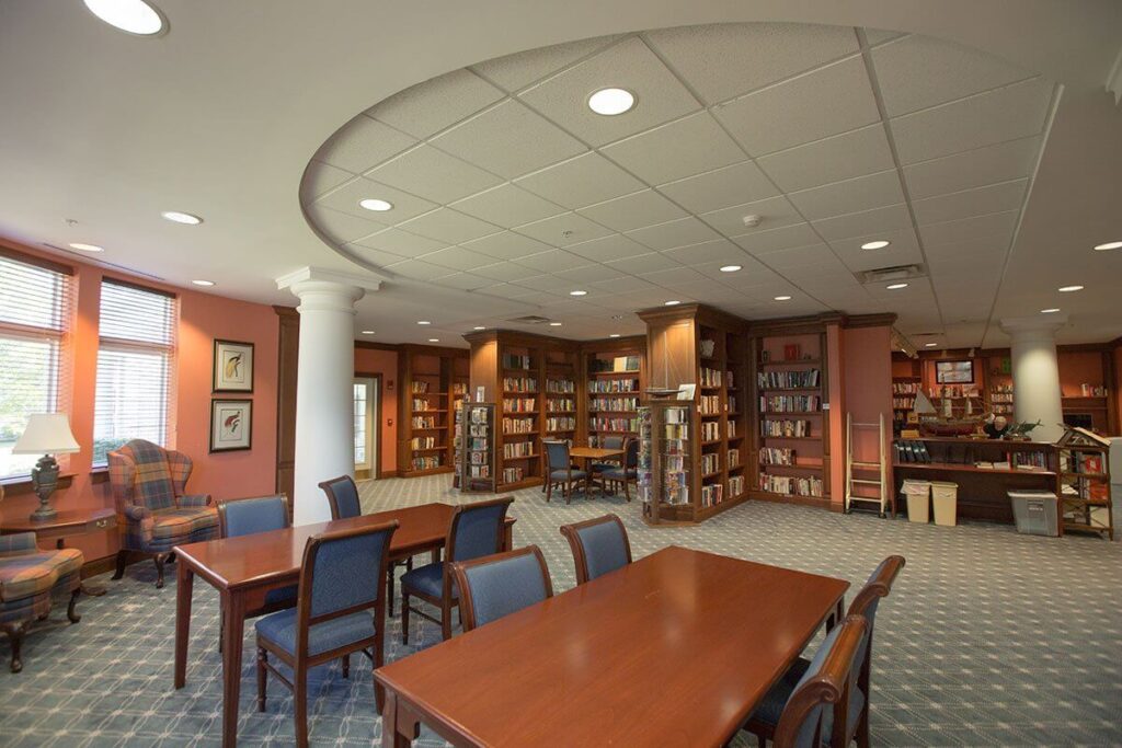 two rectangular tables with chairs around each located in a library