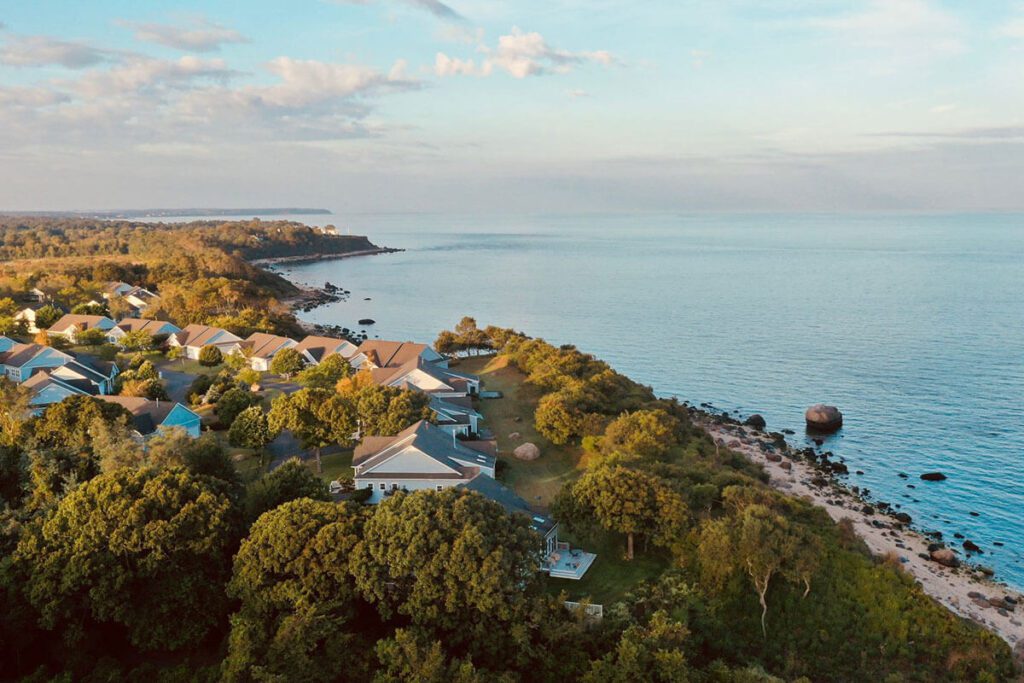 aerial drone view of a blue sky, coastline, treetops and houses along the New York coastline