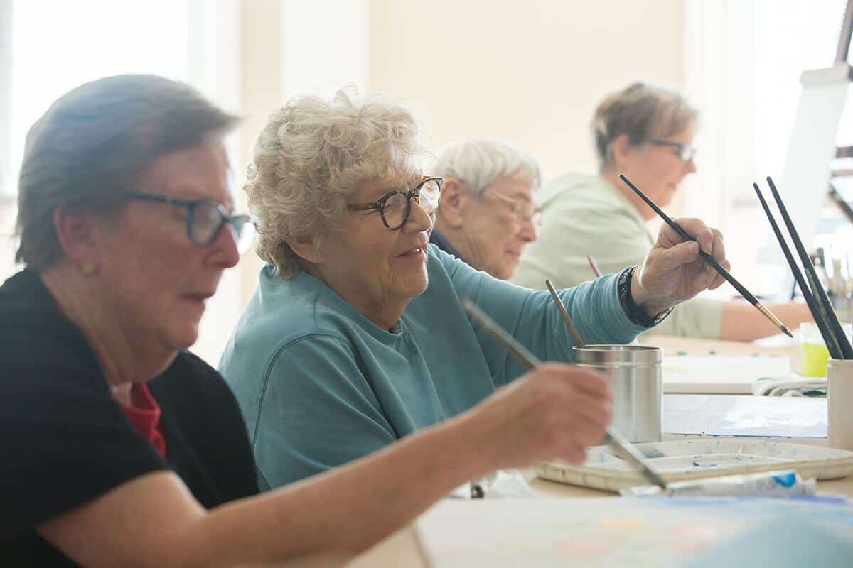 Senior woman sitting together in an art class painting