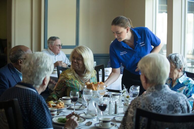 Older adults sitting in a dining room and a waitress serving them