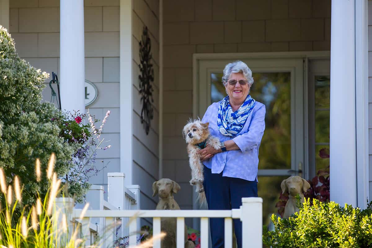 Senior woman holding small dog on front porch