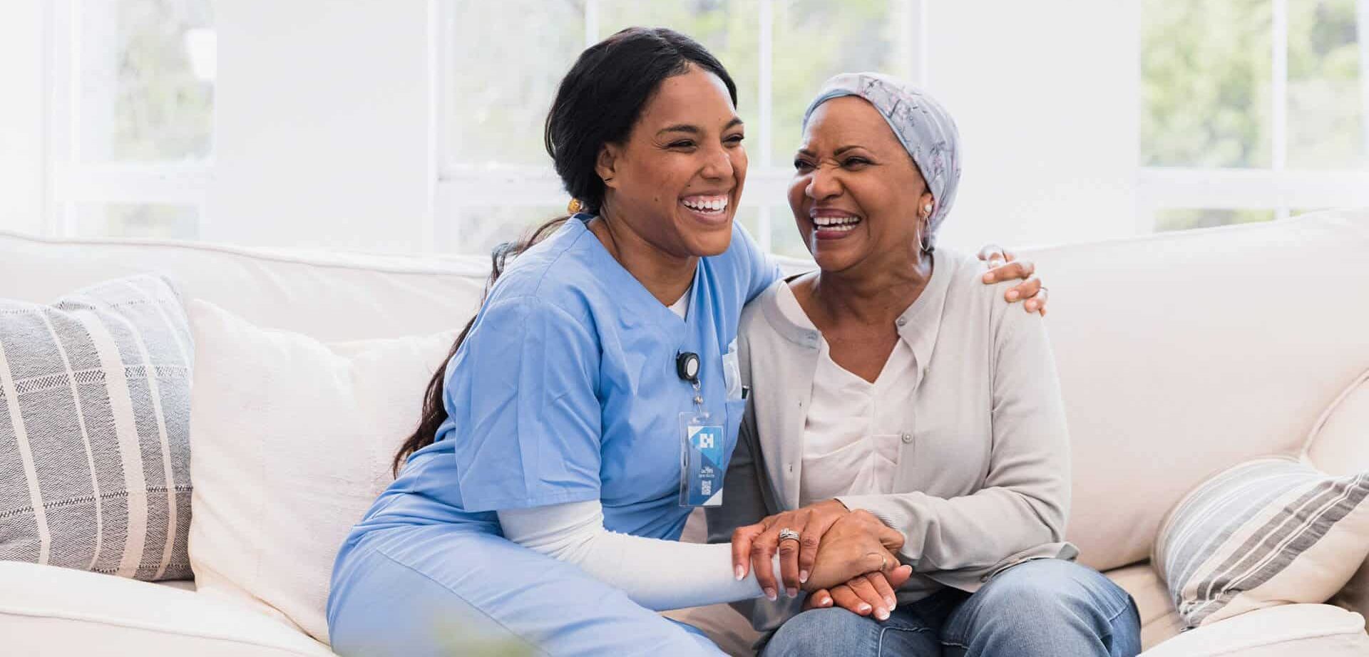 Nurse sitting on couch with senior woman for home health services