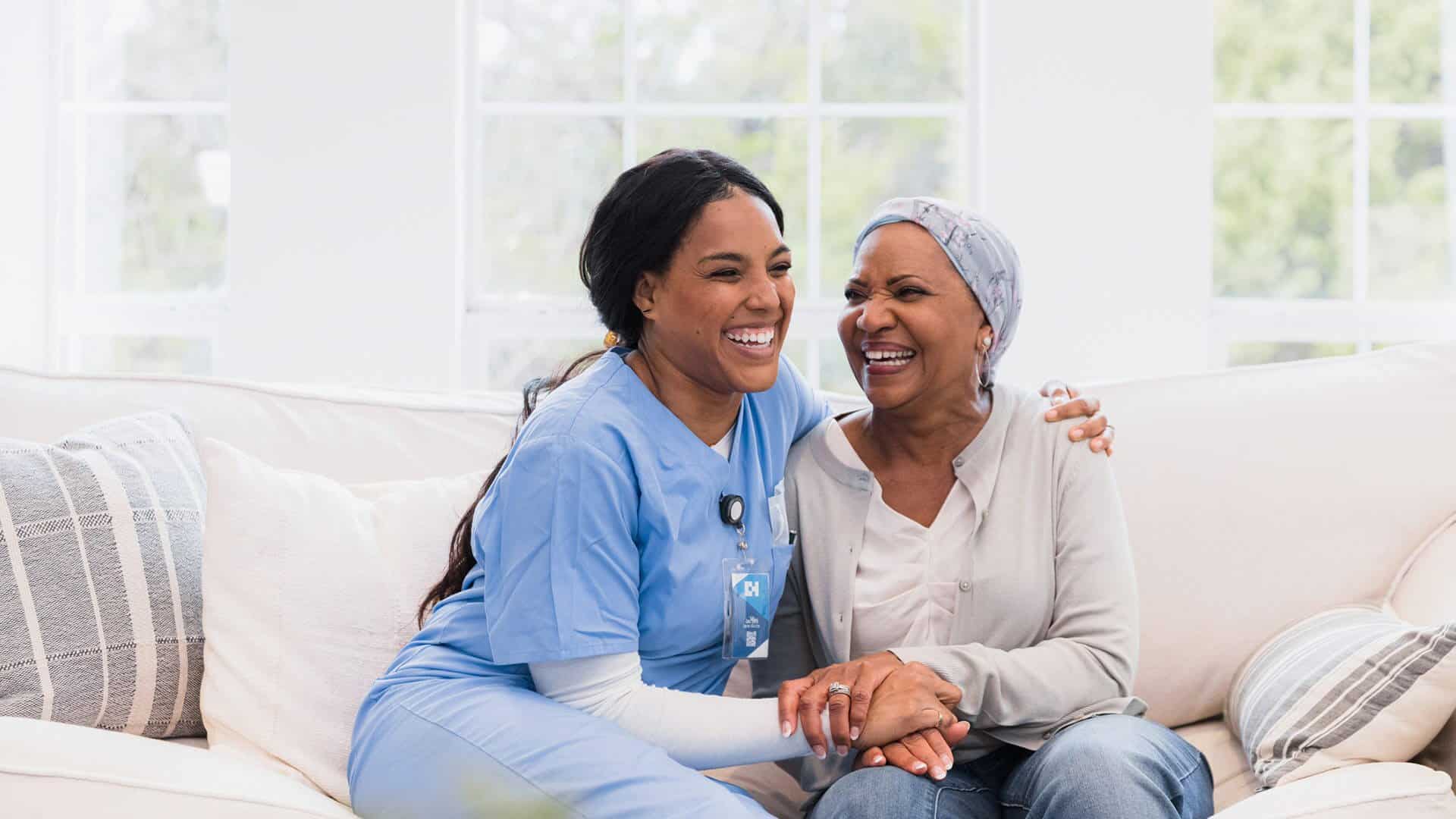 Nurse sitting on couch with senior woman for home health services