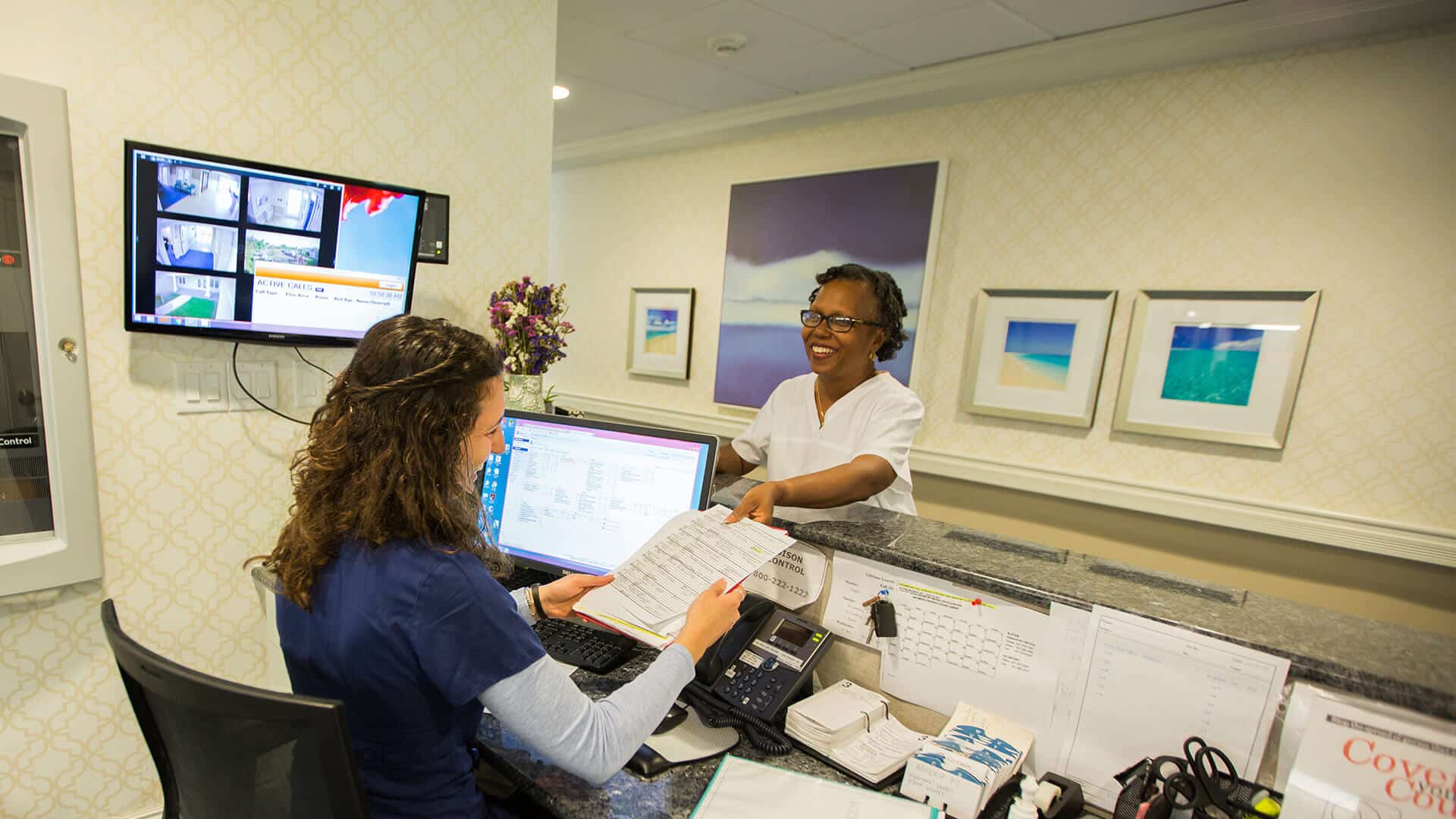 Skilled nursing, nurse handing files to woman behind desk